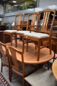 A vintage part teak extending dining table and seven (six plus one) dining chairs