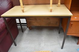 A modern oak effect desk having metal legs.