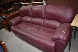 A modern three seater settee in soft burgundy leather
