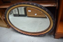 An early 20th Century oval wall mirror having part gilt frame