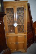 A Ferdinando reproduction golden oak style corner display having leaded glass doors to top and