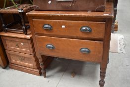 An antique mahogany chest of two drawers sat aloft of turned legs and having brass cup handles.