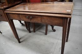 A 19th Century mahogany fold over tea table having stepped top, frieze drawer on tapered legs