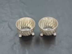 A pair of Victorian silver salts, of circular spirally fluted form with beaded rim, raised on