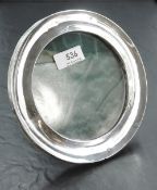 An Edwardian silver photograph frame of circular form having green leather covered easel back,
