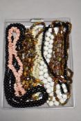 A selection of strings of beads including coloured shell, mother of pearl, glass, polished stone