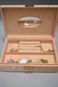 A peach coloured jewellery box containing a selection of costume jewellery chains and necklaces