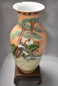 A large oriental styled lamp base, having orange ground with storks amongst shrubbery, chip to