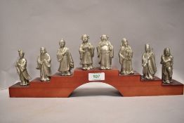 A 20th century set of eight pewter or similar figures of Chinese officials on wooden stand