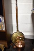 A brass warming pan sold alongside a copper kettle.