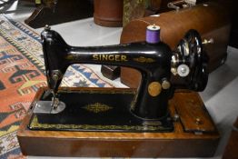 An early 20th century Singer sewing machine with hand crank and oak case
