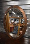 A Victorian oval Arts and Crafts mirror with copper worked frame