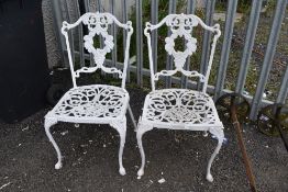 A pair of cast alloy garden chairs in antique style