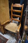 A 20th century golden oak smokers bow arm chair having rush seat
