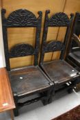 A matching pair of 17th century priory style chairs having oak frames with carved backs and plank