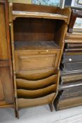 An early 20th Century oak stationery cabinet with shelf/drop flap and magazine section