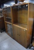Two mid century book cases having glazed fronts with cupboard