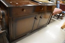 An Edwardian side board in oak having three drawer and under cupboard storage