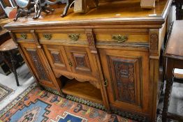A Victorian sideboard having three drawer and three cupboards with carved panels and original