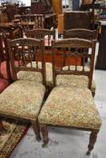 A set of four late 19th Century oak dining chairs having spindle backs, overstuffed seats and turned