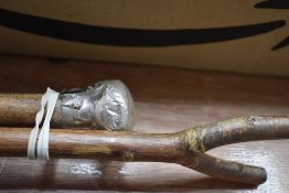 A white metal topped cane and a thumb stick