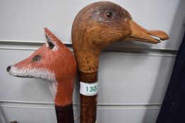 Two sticks one with a foxes head and the other with a carved ducks head