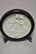 A Victorian parian ware roundel plaque depicting three angels surrounded by cherubs