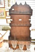 A 18th century artisan made vernacular spoon rack and utensil shelf in oak having shaped back with