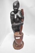 An African ethnic wood figure of a tribal lady with mixing pot
