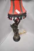 A Victorian French spelter lamp base in the form of a maiden with lute holding torch, appears in
