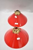 A pair of conical ceiling light shades in red and white glass having original gallery