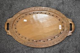 A hand carved wooden serving tray having twin handles with ivy leaf and foliate border