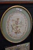 A fine antique needle work image of a rose and flowers with snaked boarder in oval gilt frame