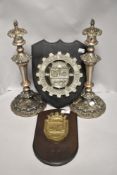 A pair of early 20th candle sticks and two industrial ship builders plaques including Armada Peruana