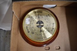 A circular weathermaster wall barometer having brass dial with glass face on wooden mount.