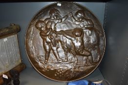A large antique embossed copper plaque depicting children catching a goat.