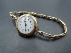 A lady's vintage 9ct gold wrist watch having Roman numeral dial to white enamelled face in plain