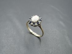 An oval Opal dress ring having sapphire and diamond chip surround on a 9ct gold loop, size O &