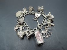 A white metal charm bracelet having sixteen HM silver and white metal charms including opening
