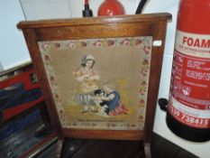 A Victorian fire screen having embroidered picture of Martha Morphet's work 1859 with oak surround