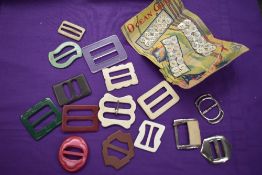 A collection of art deco buckles, predominantly early plastic, and an unused card of MOP buttons.