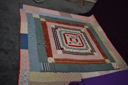 A large Victorian quilt, using vibrant patterned and floral cottons, backed in pink winceyette.