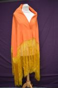 A stunning early 20th century orange silk shawl having deep gold toned fringing to edges.
