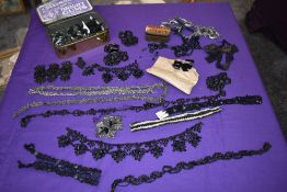 A tin full of antique beads, beaded panels and lengths of braid and lace.