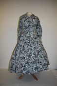 A 1950s cotton day dress having black rose print over blue stripes, larger size.