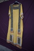 A gold and blue costume having heavily beaded panels edged with braiding to front of costume and