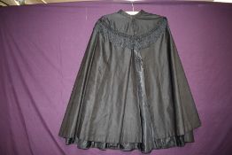 A Victorian black shawl having simple style and tassel detailing to upper bodice.
