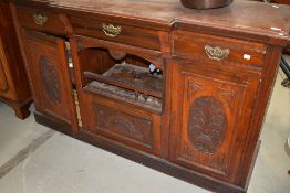 A Victorian side board or dresser base in mahogany with carved doors, triple drawers and cupboards