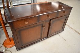 An Edwardian side board in oak having three drawer and under cupboard storage