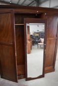 An Edwardian mahogany and inlaid triple wardrove having mirror door